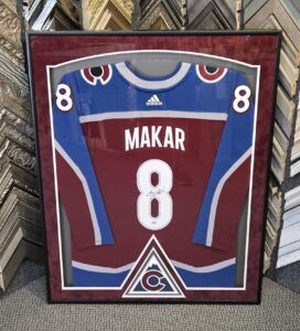 Custom framed signed Cale Makar Colorado Avalanche number 8 hockey jersey with burgundy matting, team logo detail, and black frame.